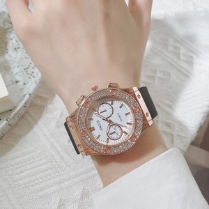 Gros plan d'une montre à quartz en or rose pour femme avec lunette diamantée sur fond blanc