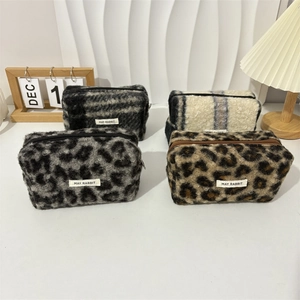 Detail view of four wool cosmetic bags in leopard and checkered plush patterns