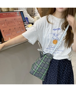 Detail shot of a large grey and green checkered tote bag worn as a casual shoulder bag