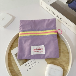Detail of purple canvas coin purse with yellow zipper and pink ring pull in lifestyle setting