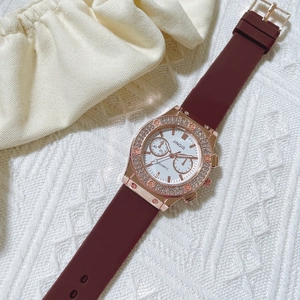Détail de la lunette sertie de diamants rose doré et du bracelet en silicone bordeaux