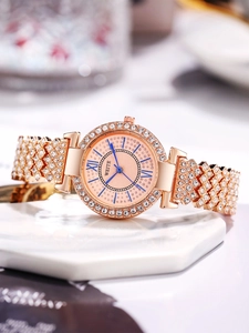 Gros plan d'une montre en or rose avec aiguilles bleues et strass sur marbre