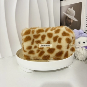 Detail view of plush leopard print cosmetic bag with white brand label on a tray
