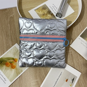 Close-up of heart-quilted silver jewelry pouch with pink and blue zipper detail