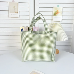 Detail of green plaid canvas tote bag with dual handles on a minimalist table set
