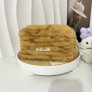 Close-up of fluffy leopard print plush makeup bag with woven brand label on white tray