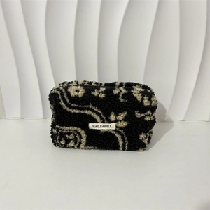 Detail of soft black sherpa makeup bag with white bohemian pattern and May Rabbit label