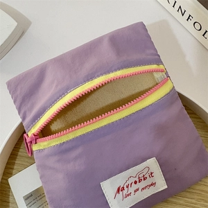 Detail of purple nylon mini pouch with contrasting yellow zipper and canvas label