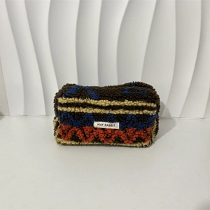 Detail of multi-color plush makeup bag featuring lamb wool texture and geometric patterns