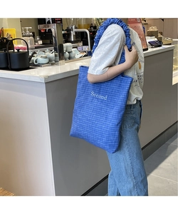 Dettaglio della borsa tote a scacchi blu con ricamo Second e tracolla a volant