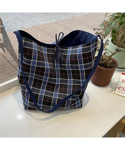 Detail of tartan tote bag featuring drawstring closure and durable canvas material