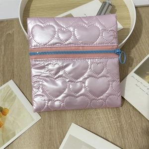 Pink heart quilted storage bag with contrasting blue zipper on minimalist wood desk