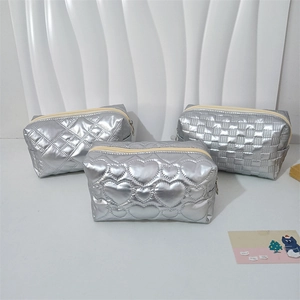 Detail of silver metallic PU makeup bags featuring heart, diamond, and checkerboard quilting