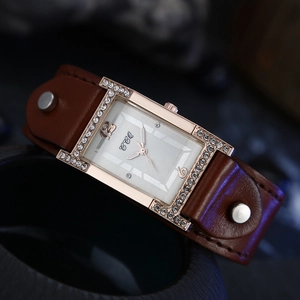 Macro detail of rectangle quartz watch with rose gold crystal bezel and brown wide leather strap
