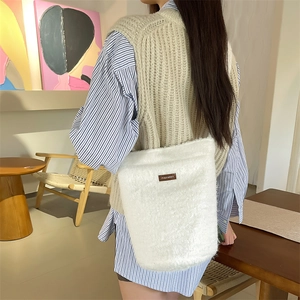 Détail du sac seau blanc en peluche avec écusson marron sur de la fausse fourrure