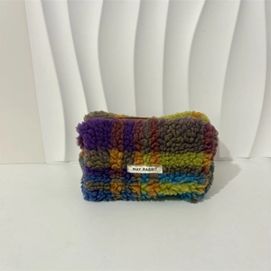 Macro shot of colorful checkerboard plush makeup bag with soft fur and top zipper closure