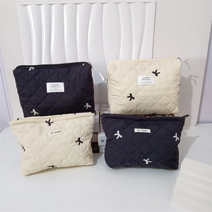 Quilted cosmetic bags in black and beige with bow embroidery and rhombus pattern