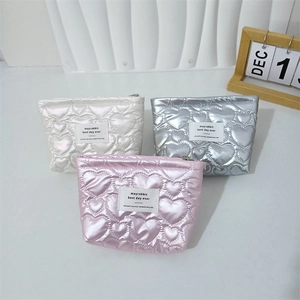 Quilted heart pattern cosmetic bags in white, silver, and pink with brand label