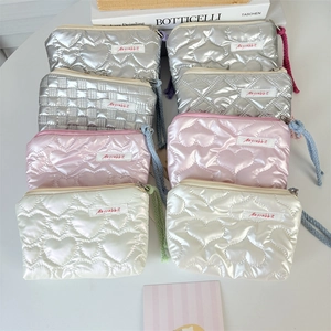 Flat lay of quilted heart-pattern makeup bags in metallic silver and pastel colors