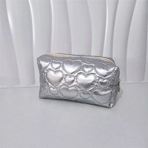 Detail of silver heart quilted PU makeup bag with metallic finish and top zipper