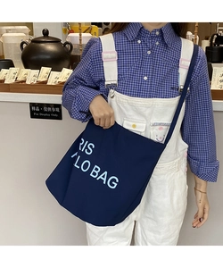 Detail of large dark blue canvas tote bag with letter print worn by a female model