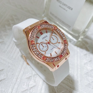 Gros plan d'une montre en or rose avec lunette en strass et bracelet en silicone blanc