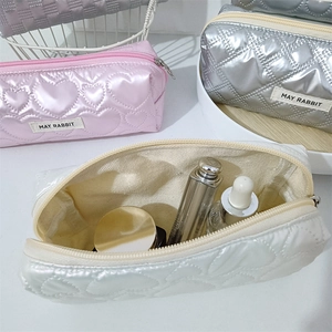 Dettaglio di pochette per cosmetici in raso trapuntato rosa, argento e bianco con cerniera