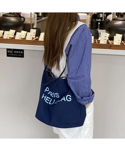 Detail of navy canvas tote bag with Paris lettering shown on a model in a casual setting