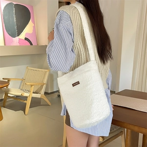 Détails de la texture du sac seau en peluche blanche avec étiquette en cuir marron