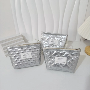 Three silver quilted makeup bags with heart and square patterns on a white background