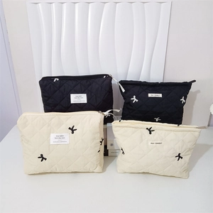 Close-up of quilted cosmetic bags featuring delicate bow embroidery and zipper closure