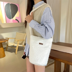 Détail du sac seau en peluche blanche douce avec logo de marque marron et sangle