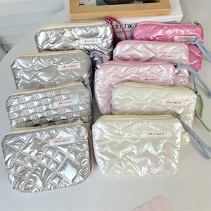 Flat lay of quilted heart coin purses in silver, pink, and white with woven handles