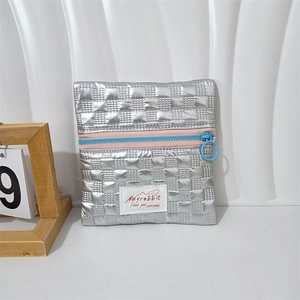 Close-up of metallic silver quilted mini pouch featuring contrast blue and pink zipper detail