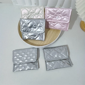 Quilted faux leather coin purses in metallic silver and pink on a wooden tray
