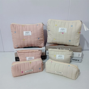 Detailed close-up of quilted fabric makeup bags with colorful heart embroidery textures