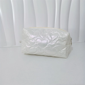 Detail of pearlescent white makeup bag with heart-shaped quilting and gold zipper