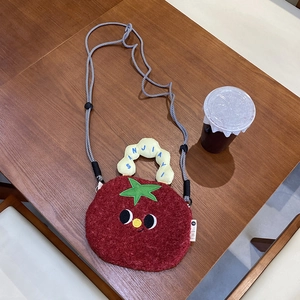 Top-down view of a plush tomato crossbody bag with cute face and long rope strap