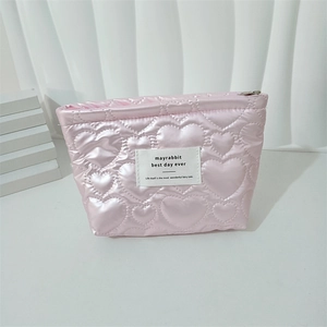 Detailed view of pink heart quilted makeup bag with zipper closure and logo tag