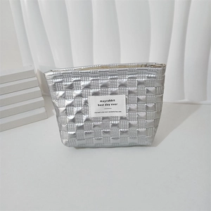 Close-up of quilted silver makeup bag with square pattern and minimalist woven label