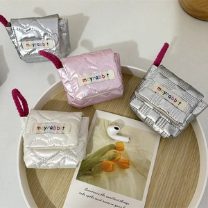 Close-up of quilted mini heart pouches in silver, pink, and white with rainbow labels