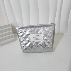 Close-up of silver quilted makeup bag with heart pattern on a minimalist white display