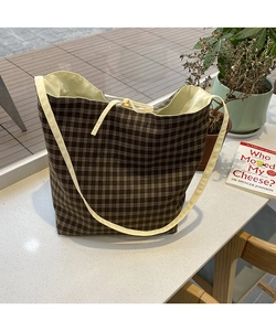 Detail of checkered canvas tote bag with drawstring closure and slim shoulder strap