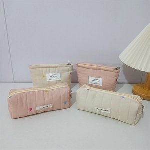 Detailed view of quilted cotton cosmetic bags with heart embroidery and zippers