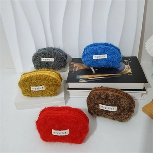 Dettaglio di pochette in morbido peluche a forma di conchiglia in cinque colori vivaci