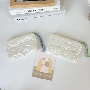 Close-up of heart-quilted PU makeup bag with contrast braided zipper pulls and soft texture