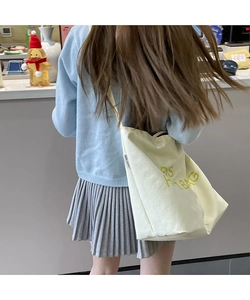 Detail of minimalist canvas tote with yellow lettering and adjustable strap