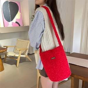 Vue détaillée du sac seau rouge en peluche avec texture douce et logo de marque en cuir