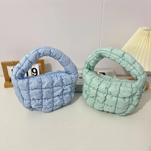 Detail of light blue and green quilted cloud handbags showing puffy grid texture and handle