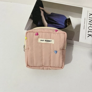 Close-up of pink quilted makeup bag with colorful heart embroidery and metal zipper